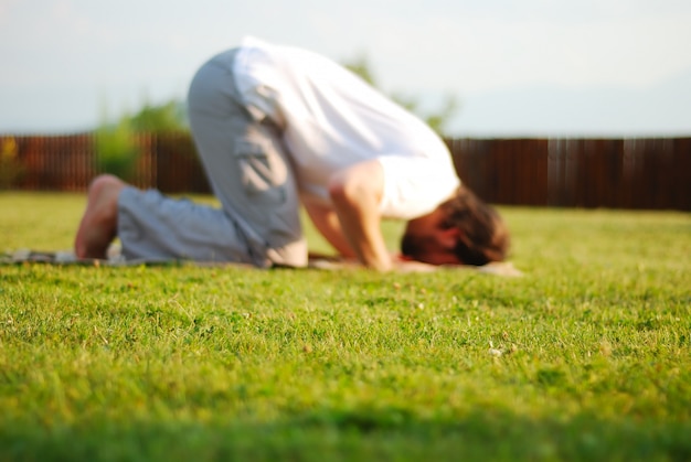 Outfocused muslim prayer on green meadow