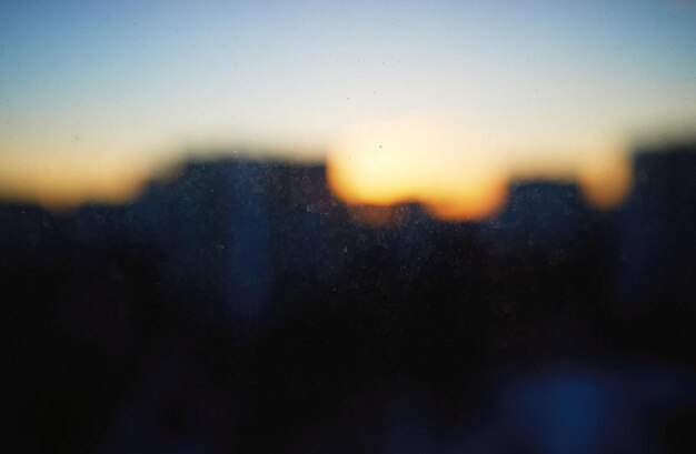 Outlines of evening city through dirty window backdrop