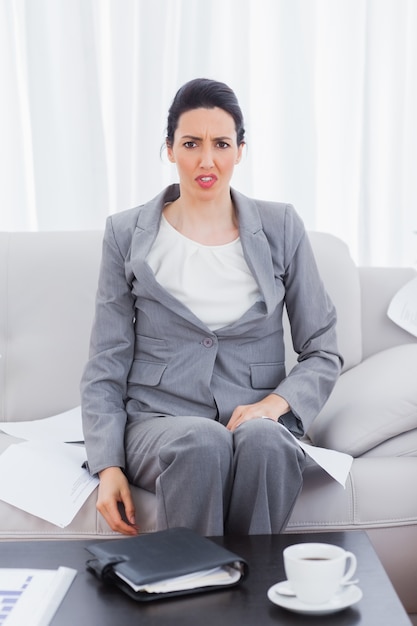 Outraged businesswoman sitting on sofa looking at camera 