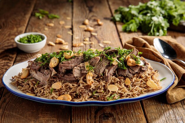 Ouzi lam of lam pulao met noten geserveerd in een schotel zijaanzicht geïsoleerd op houten tafel