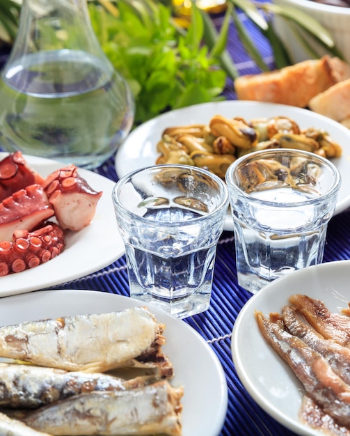 Ouzo raki alcohol with seafood meze vertical view