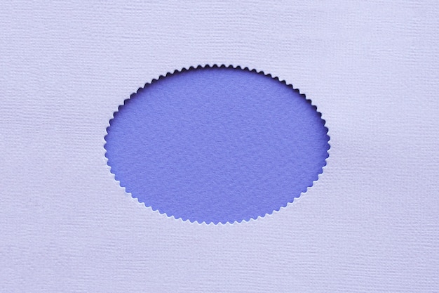Foto ovaal gat met golvende randen in lila papier op een violette papieren achtergrond.