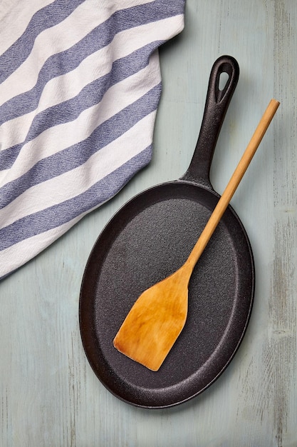 Padella ovale in ghisa con una spatola di legno e un canovaccio mockup per stendere il cibo