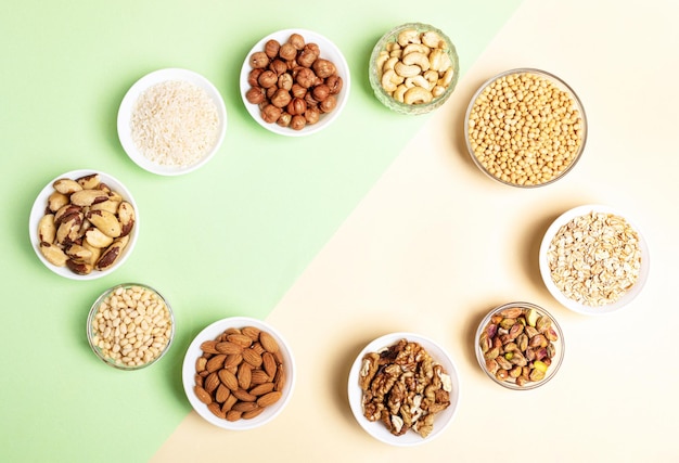 Oval frame of bowls with cereal grains and nuts on twotone beigegreen backdrop Top view