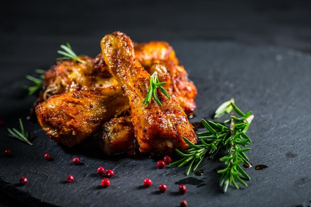 Oven baked chicken drumsticks with herbs and spicies on black background