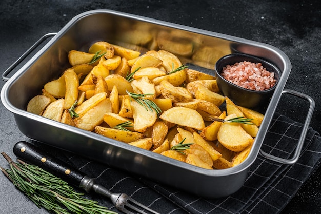 Oven Baked potato wedges with herbs homemade organic vegan vegetarian potato wedges snack Black background Top view