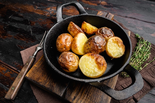 Oven baked potatoes with rosemary set, in frying cast iron pan, on old dark  wooden table background