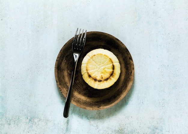 Oven baked ricotta cheese on a clay plate and fork. basic cooking techniques of Italian cuisine. breakfast.