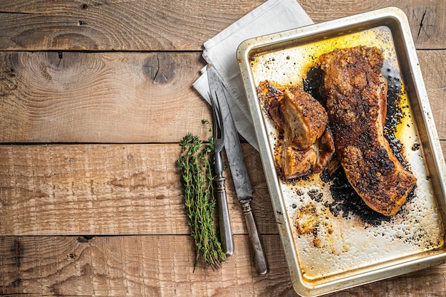 Oven Roast Pork belly meat in a kitchen tray Wooden background Top view Copy space