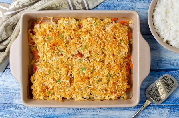 Oven-roasted fish fillet with carrots under a bread crust. For garnish white rice