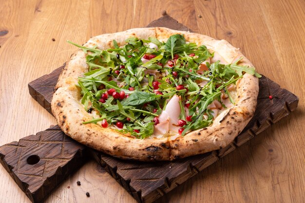 Ovengebakken italiaanse pizza melagrano met mozzarella kaas ham rundvlees rucola granaatappelpitjes basilicum en olijfolie