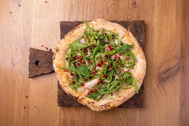 Ovengebakken Italiaanse pizza Melagrano met Mozzarella kaas ham rundvlees rucola granaatappelpitjes basilicum en olijfolie