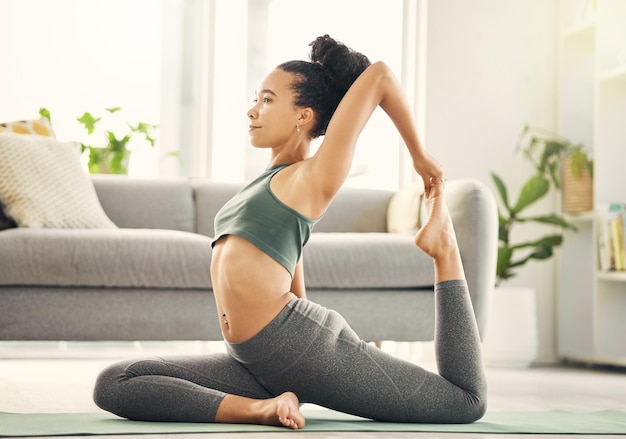 Overal is flexibiliteit nodig. Shot van een jonge vrouw die yoga beoefent in haar woonkamer.