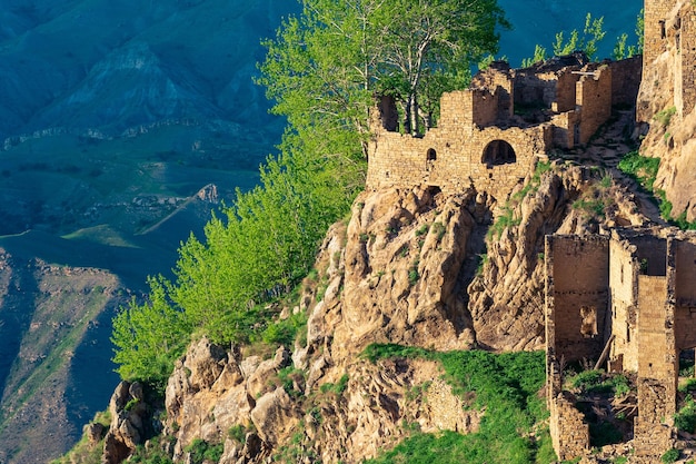 Overblijfselen van stenen huizen op een steile klif in het verlaten dorp Gamsutl in Dagestan