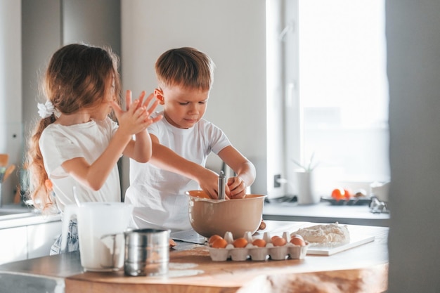 Overdag Kleine jongen en meisje bereiden kerstkoekjes in de keuken