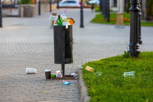夏の日中の歩道の舗装に溢れるゴミ箱