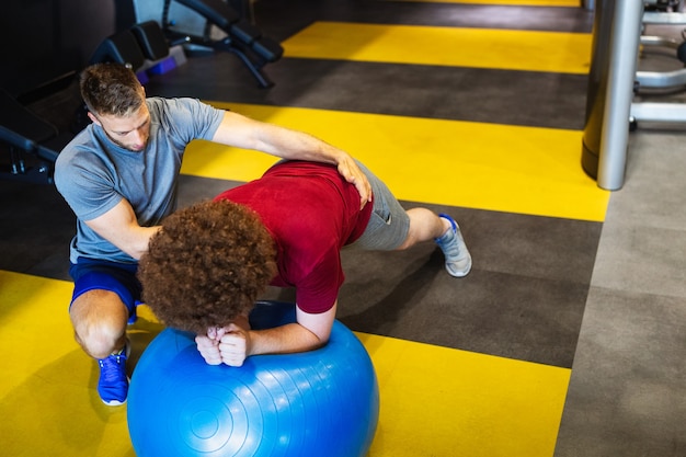 Overgewicht jonge man met trainer trainen op fitness gym