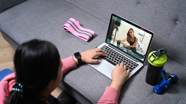 Overgewicht jonge vrouw kijken naar online training op laptopcomputer thuis.