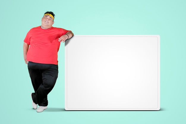Overgewicht man leunend op een leeg whiteboard
