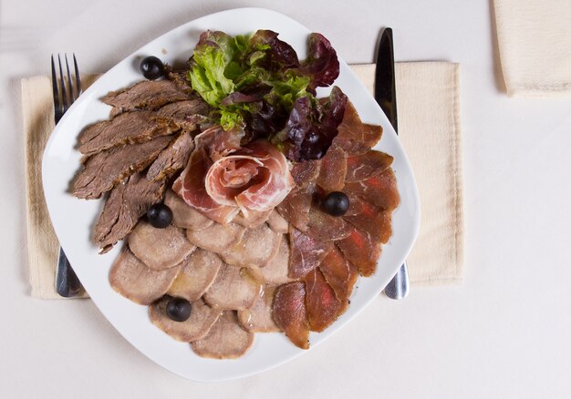 Foto sovraccarico di un piatto di carne fredda assortita al coperto