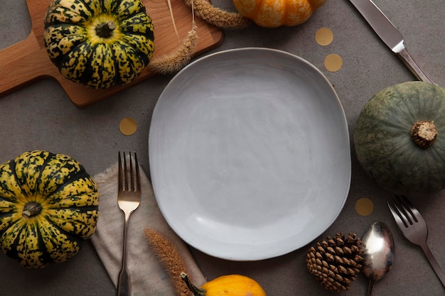 Overhead autumn thanksgiving dinner place setting with pumpkins cutlery and an empty plate