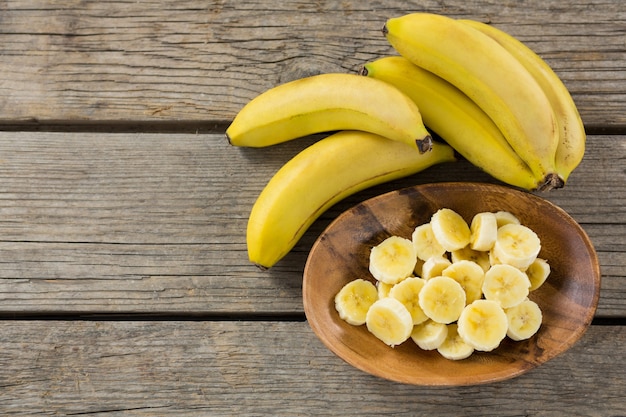 Overhead of banana and slices of banana in plate on wooden table