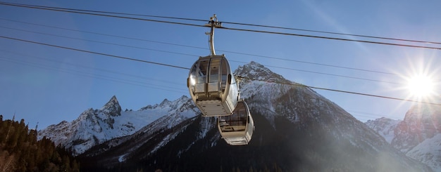 写真 空の向こうの雪に覆われた山の上のケーブルカー