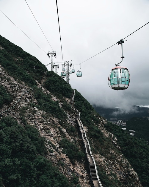 Photo overhead cable cars by mountain against cloudy sky