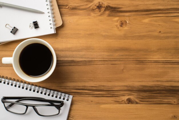 Overhead above close up view photo image of note pads mug of morning fresh tasty espresso eyewear and copybooks isolated light color backdrop with empty space