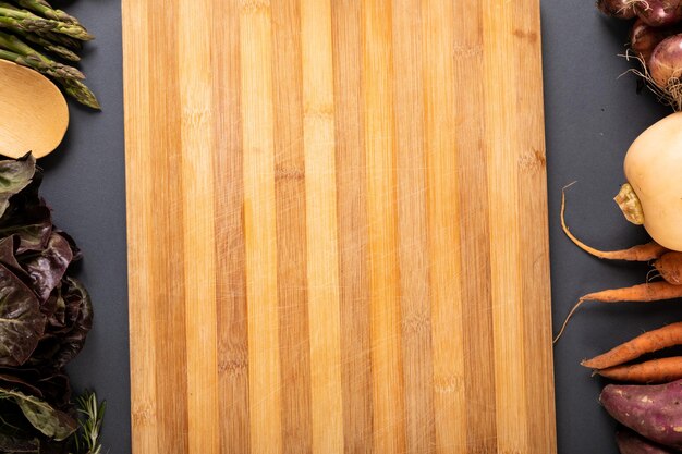 Photo overhead close-up of wooden cutting board with copy space and vegetables on gray background. unaltered, variation, healthy food, vegetable, raw food and organic concept.