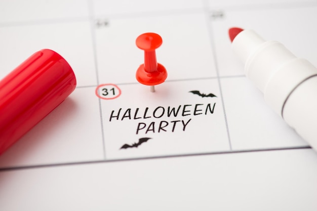 Overhead foto van label datum 31 oktober met inscriptie halloween party twee vleermuizen rode pin en marker geïsoleerd op de kalender achtergrond