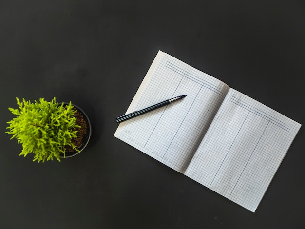 Overhead geopende lege woordenschat met pen op zwarte tafel met bloem