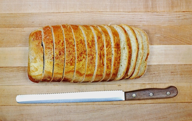 Overhead gesneden brood met lees mes gekartelde rand op houten snijplank achtergrond