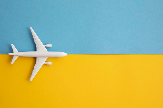 overhead lag plat van een wit passagiersvliegtuig op een helderblauwe en gele achtergrond.