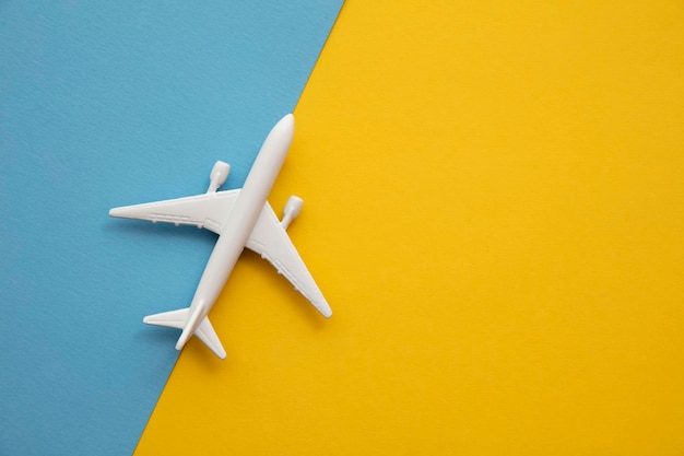 overhead lay flat of a white passenger aircraft on a bright blue and yellow background.