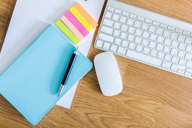 overhead of office table with clipboard, notepad, computer keyboard and mouse, pen and smartphone. c