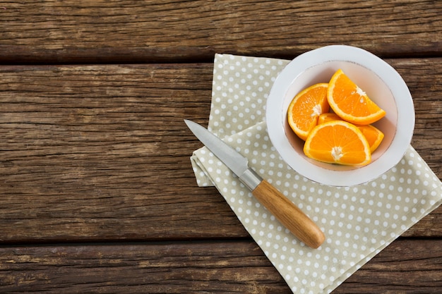 Overhead of oranges slices in bowl on wooden table