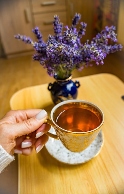 Foto una foto dall'alto di una tazza di tè vivace in mano con fiori freschi di lavanda