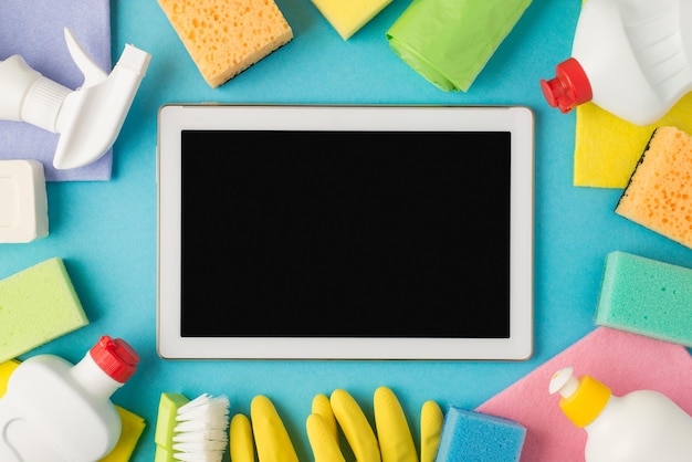 Overhead photo of equipment for cleaning and tablet in the middle isolated on the blue background