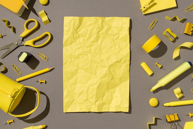 Overhead photo of school equipment scissors stickers tape paper clips notepad pins pencil pen marker sharpener pencil box and crumbled yellow paper isolated on the grey backdrop