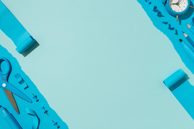 Накладное фото ножниц, булавок, маркеров, наклеек, карандашей и будильника, изолированных на синем фоне с копирайтом