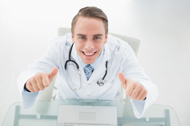 Накладные портрет улыбающегося врача с ноутбуком gesturing палец вверх