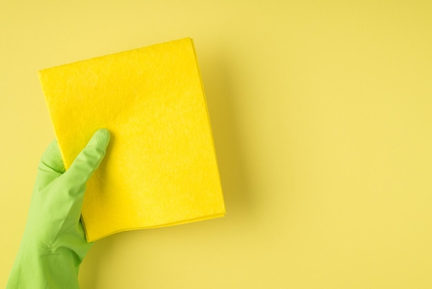 Overhead pov photo of cleaning rag and green gloves isolated on the yellow background