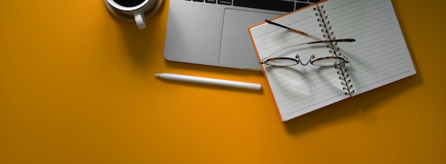 Overhead schot van creatieve werktafel met laptop, blanco notebook, benodigdheden en kopie ruimte