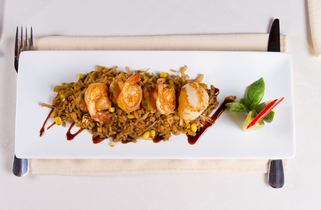 Overhead of Seafood Fried Rice with Shrimp and Scallops on Square Plate at Restaurant Place Setting