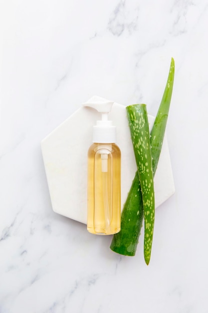 Overhead shot of aloe vera cosmetic bottle and natural green aloe vera leaves