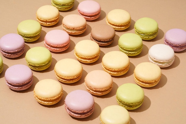 An overhead shot of a beige table surface featuring an array of colorful macarons in neat rows