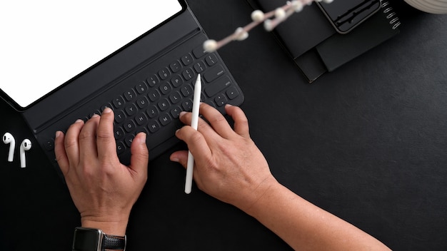 Overhead shot of businessman typing on digital tablet with stylus and other office supplies