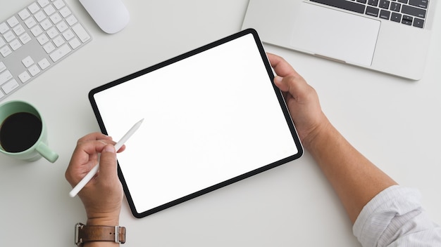 Overhead shot of Businessman working on tablet in practical workspace with computer and laptop