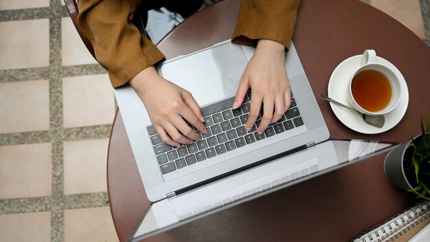オーバーヘッドショットラップトップコンピューターで作業している屋外のカフェスペースでリモートで作業している実業家